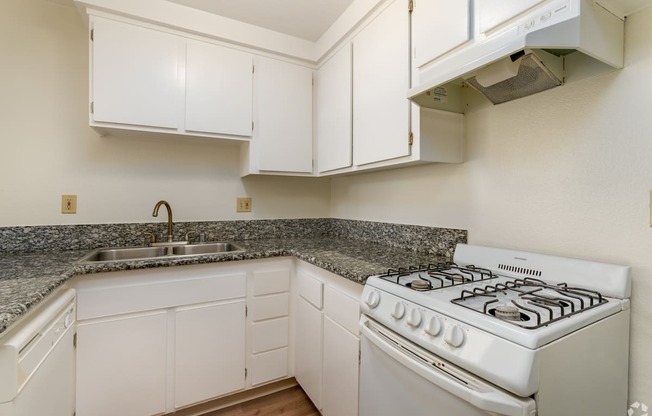 a kitchen with white appliances and granite counter tops and white cabinets