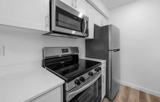 A black and white photo of a kitchen with a stove, oven, microwave, and refrigerator.