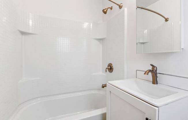 a white bathroom with a sink and a bath tub