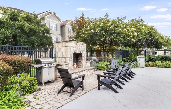 an outdoor patio with a stone fireplace and lounge chairs at Plantation Crossing, Lafayette, LA
