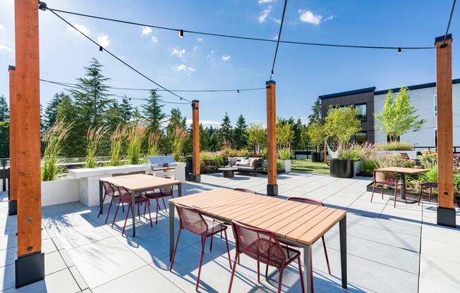 The rooftop terrace features outdoor dining areas, lounge seating, landscaped gathering spaces, and string lighting, creating a versatile setting for entertaining, coworking, or relaxing outdoors.