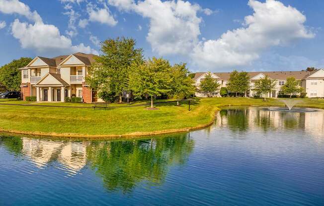 a pond in front of a house with a fountain