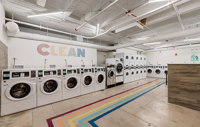 a laundromat with a row of washing machines and a wall of dryers