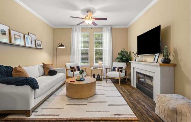 A living room with a white couch, a fireplace, and a television.