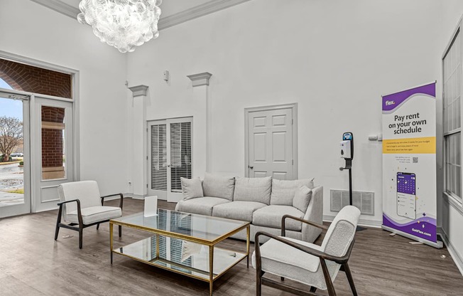 A living room with a glass coffee table and white furniture.