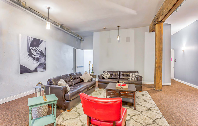 a living room with two leather couches and a red chair