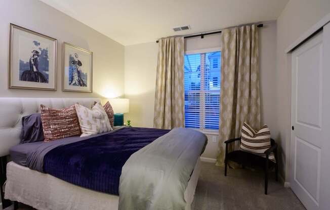 A bedroom with a bed, a chair, and two framed pictures on the wall.