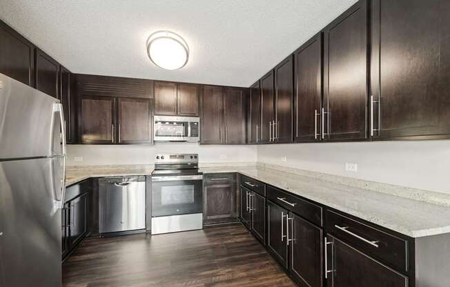A kitchen with dark wood cabinets and stainless steel appliances.