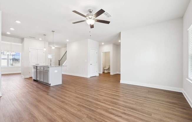 A spacious room with a ceiling fan and wooden flooring.