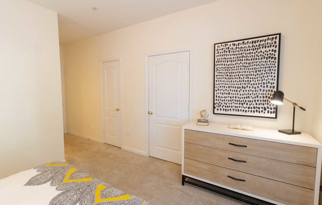 A bedroom with a bed, dresser, and a wall hanging picture.