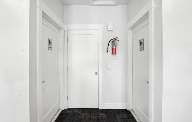 A white door with a fire extinguisher on the wall.