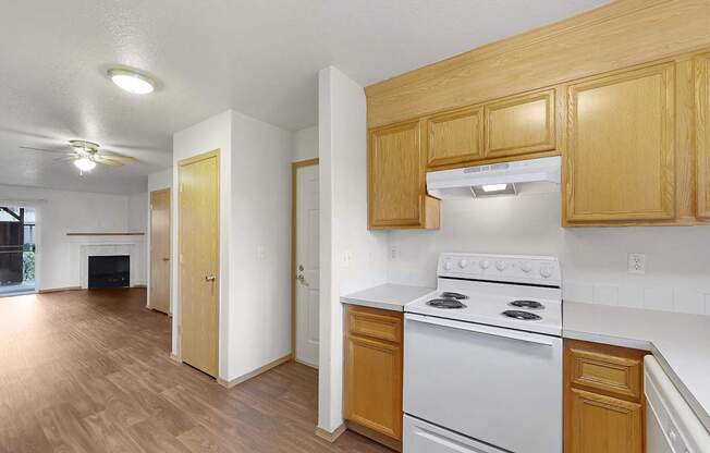 A kitchen with a white stove top oven and wooden cabinets.