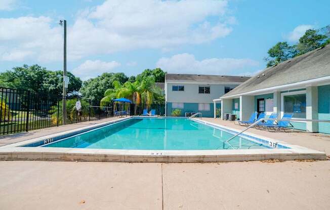 A swimming pool in front of a building with a fence around it.