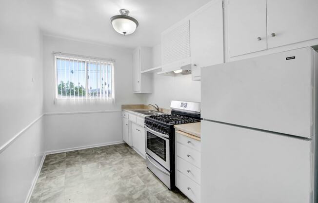 an empty kitchen with white cabinets and white appliances