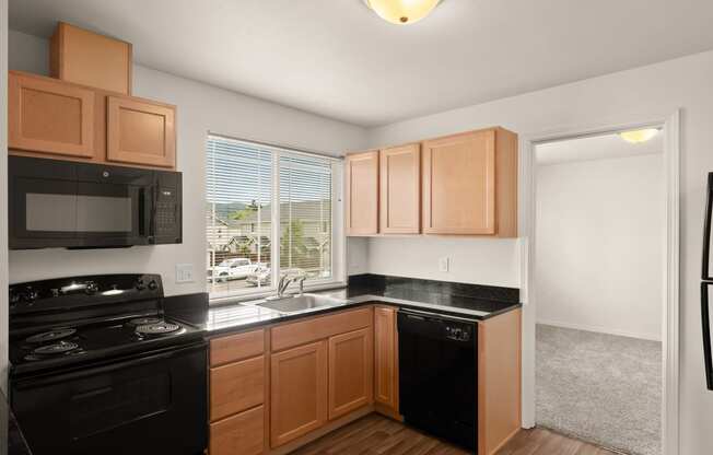 an empty kitchen with black appliances and wooden cabinets