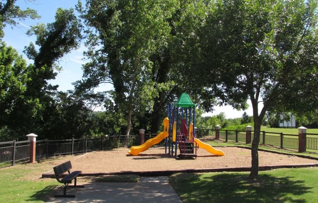 a playground with two slides and a bench in a park at GABLE HILLS Apartments, TULSA