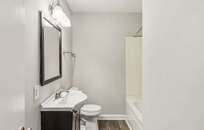 A bathroom with a toilet, sink, and mirror.