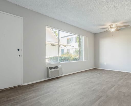 an empty living room with a large window and a ceiling fan at The Arches Apartments, California, 92021