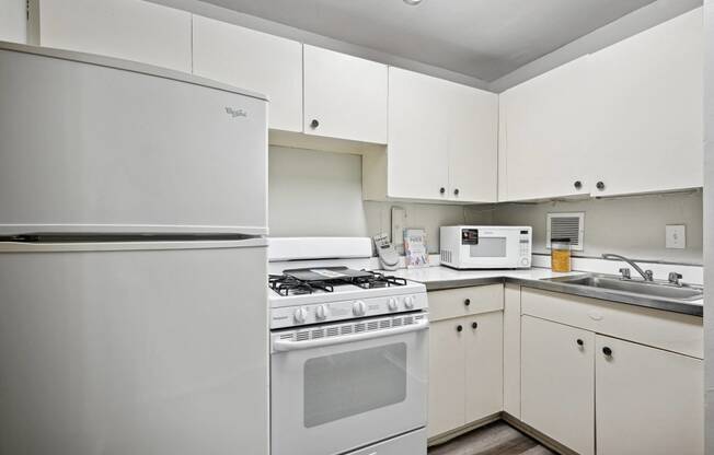 an empty kitchen with white appliances and white cabinets