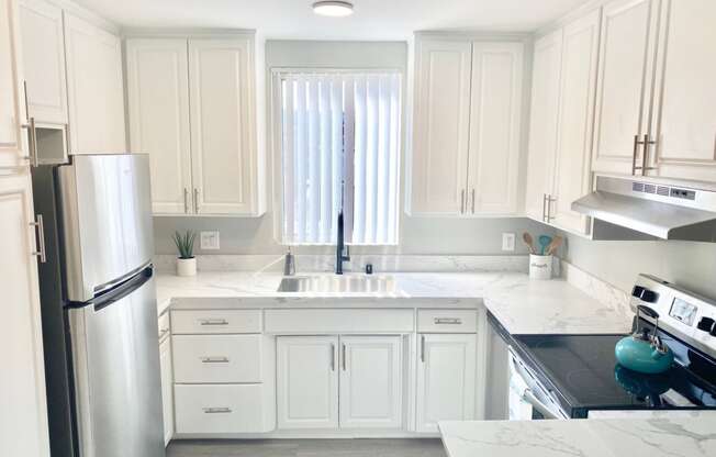 a white kitchen with stainless steel appliances and white cabinets at The Flats on Addison, California, 91423