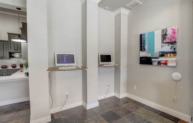 A room with a computer on a shelf and a painting on the wall.