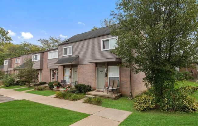 a brick house with a yard and sidewalk in front of it