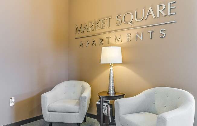 two chairs and a lamp in a room with a sign that says market square apartments