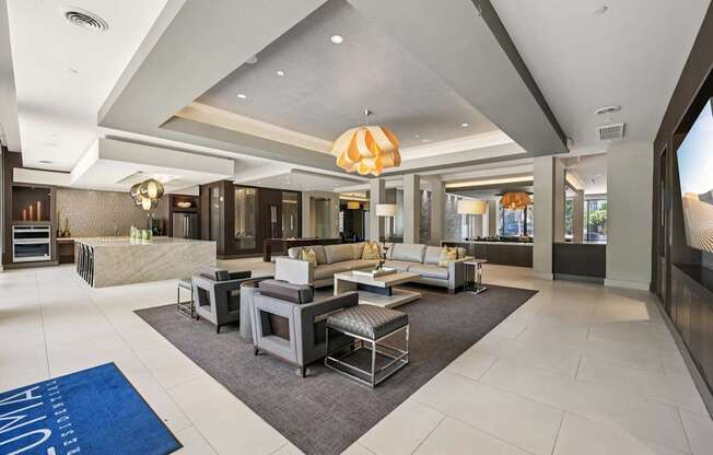 A spacious living room with a large grey sofa set and a grey rug.