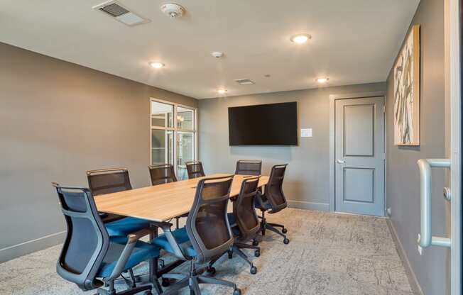 a conference room with a wooden table and chairs and a wall mounted tv at The Bella at Westchester, Midlothian, 23113