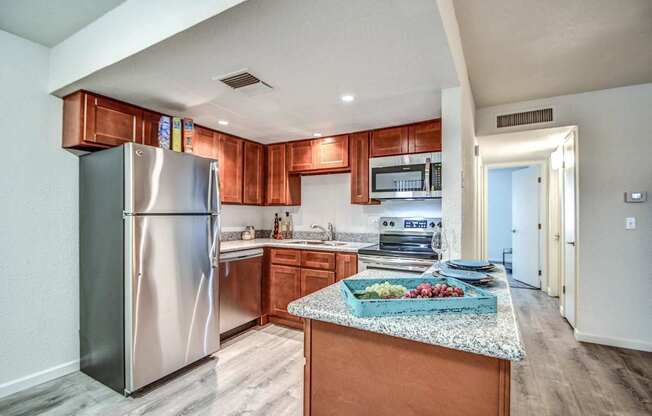 A kitchen with a refrigerator, microwave, and wooden cabinets.
