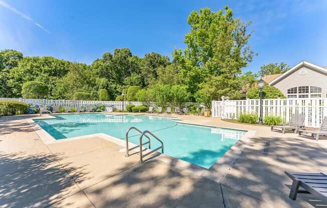 a swimming pool with a fence and a house in the background