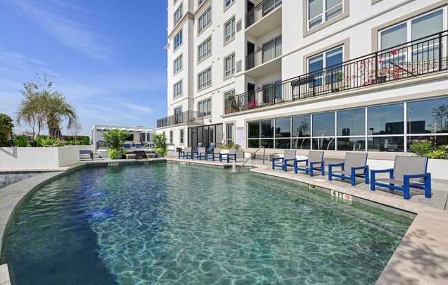 Our swimming pool in on the rooftop patio with blue chairs around it at Dominion Post Oak apartments in Houston, TX