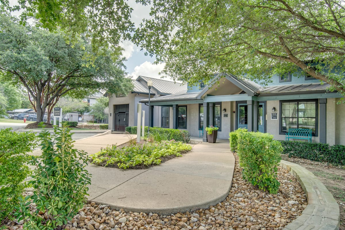 a sidewalk in front of a house with trees