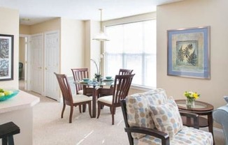 View from near kitchen breakfast bar of great room living and dining areas and hallway to bedroom