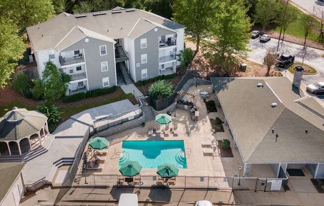 An aerial view of a pool surrounded by a gazebo and apartment buildings.