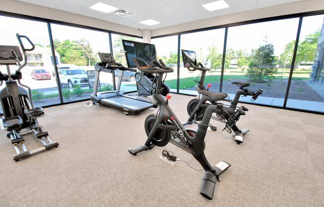 a gym with various exercise machines and a window view of a parking lot