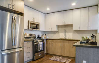 A modern kitchen with a stainless steel refrigerator and wooden cabinets.