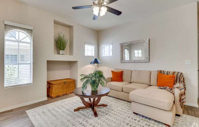 A living room with a beige couch, a wooden coffee table, and a ceiling fan.