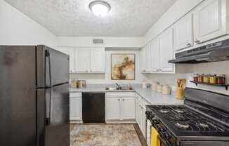 A kitchen with black appliances and white cabinets.