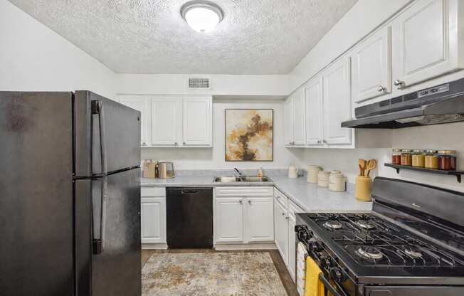 A kitchen with black appliances and white cabinets.
