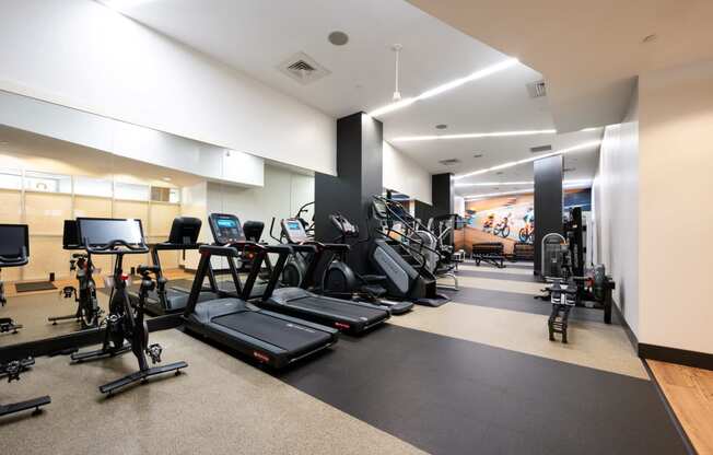 a gym with cardio equipment and weights on the floor