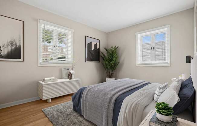 A bedroom with a bed, nightstand, and a plant.