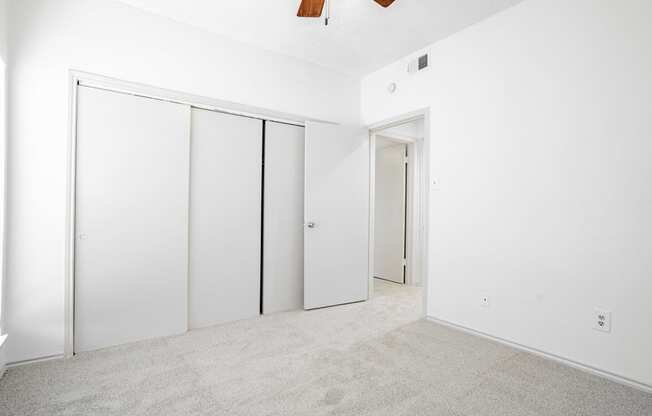 an empty room with white walls and white closet doors