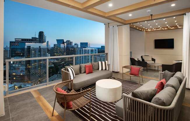 a living area with couches chairs and a rug with a view of the city