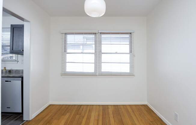 an empty living room with a window and a kitchen