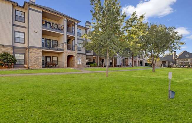 a grassy area with trees in front of a building
