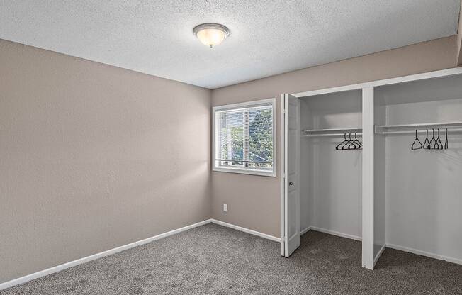 an empty bedroom with a closet and a window
