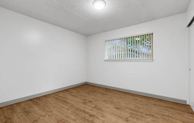 A room with a window and wooden flooring.
