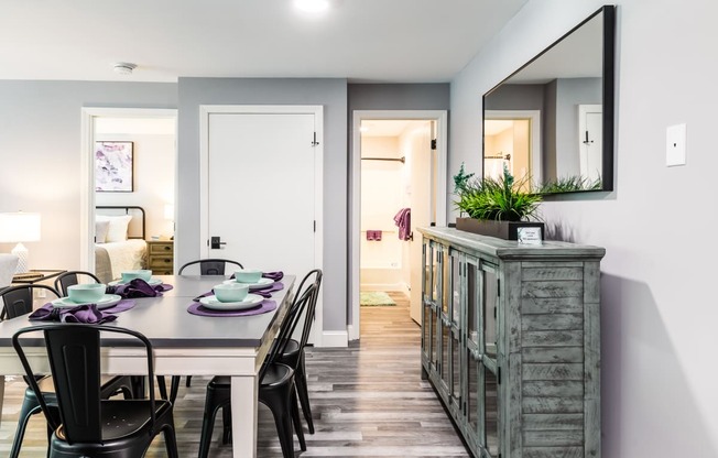 a dining room with a table and chairs and a large mirror on the wall