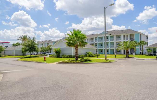 an empty parking lot in front of a building with palm trees